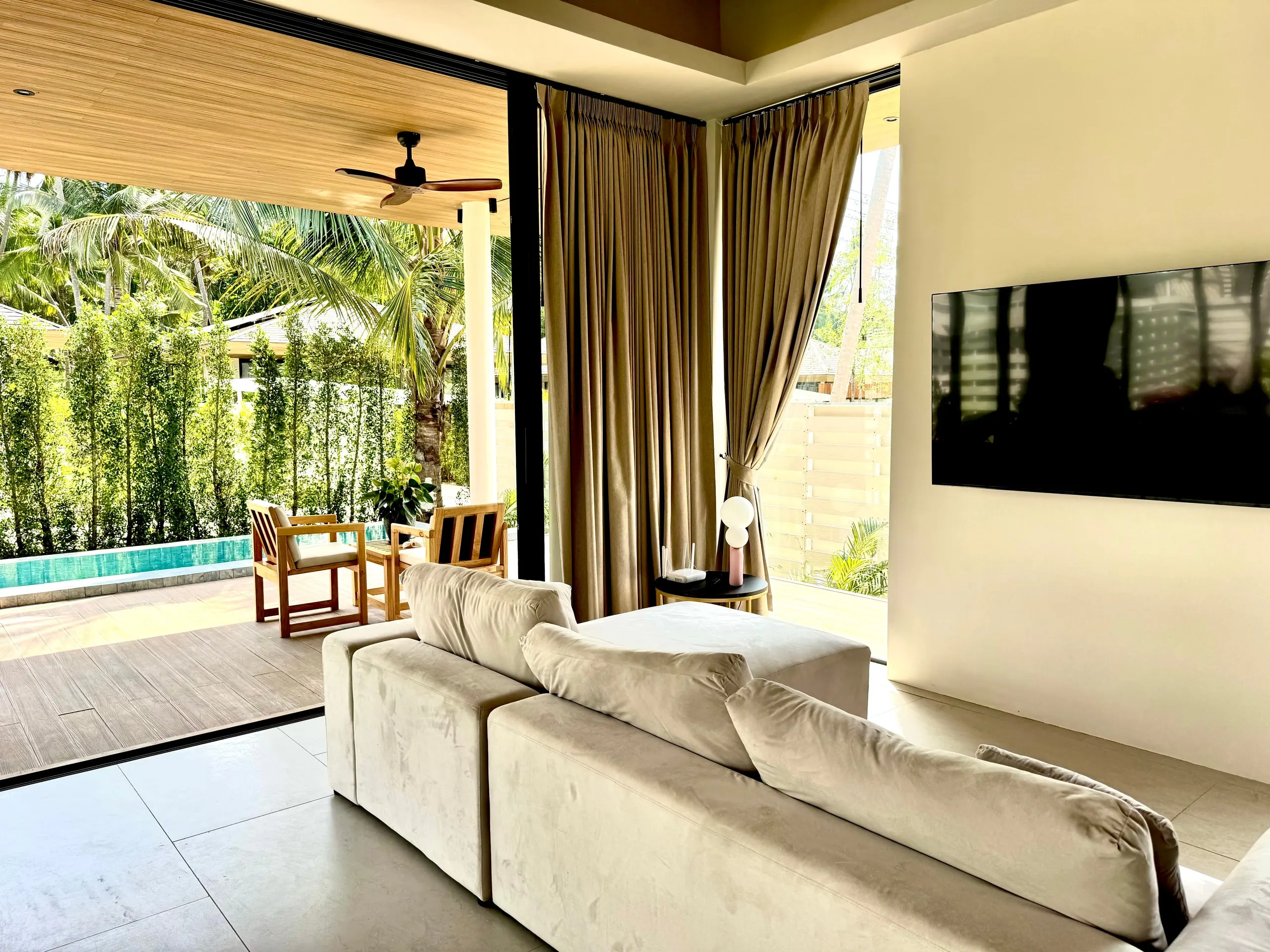 Villa I — living room with beige corner sofa opening to the pool terrace