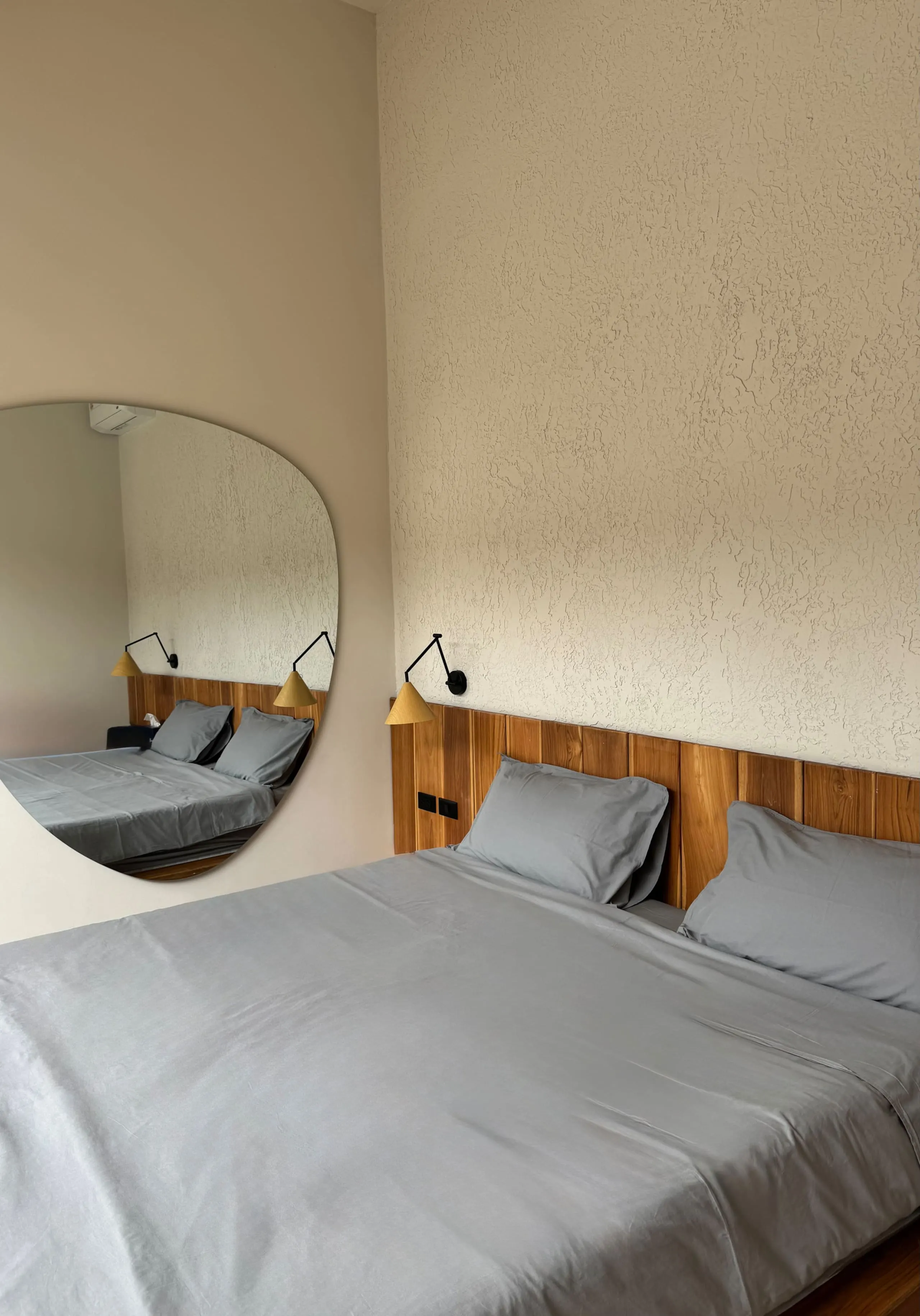 Villa I — bedroom one, platform bed and sculptural wall mirror