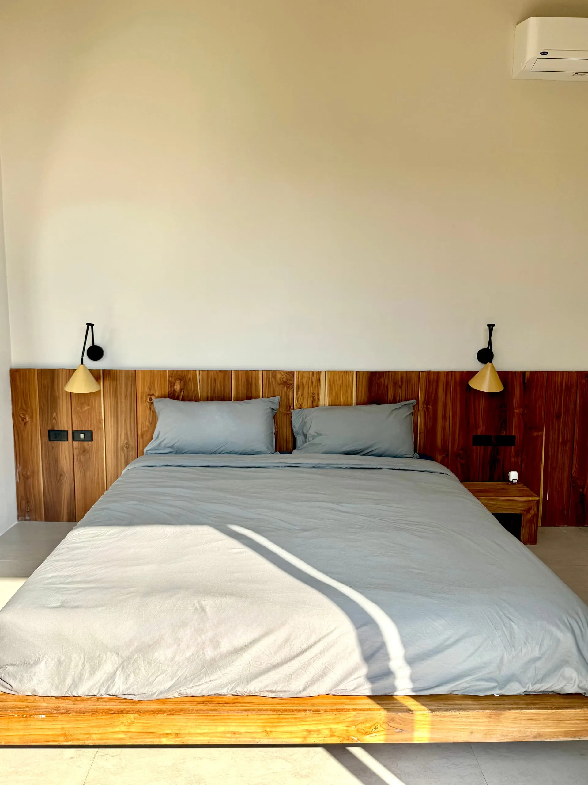 Villa II — bedroom one, low teak platform bed in morning light