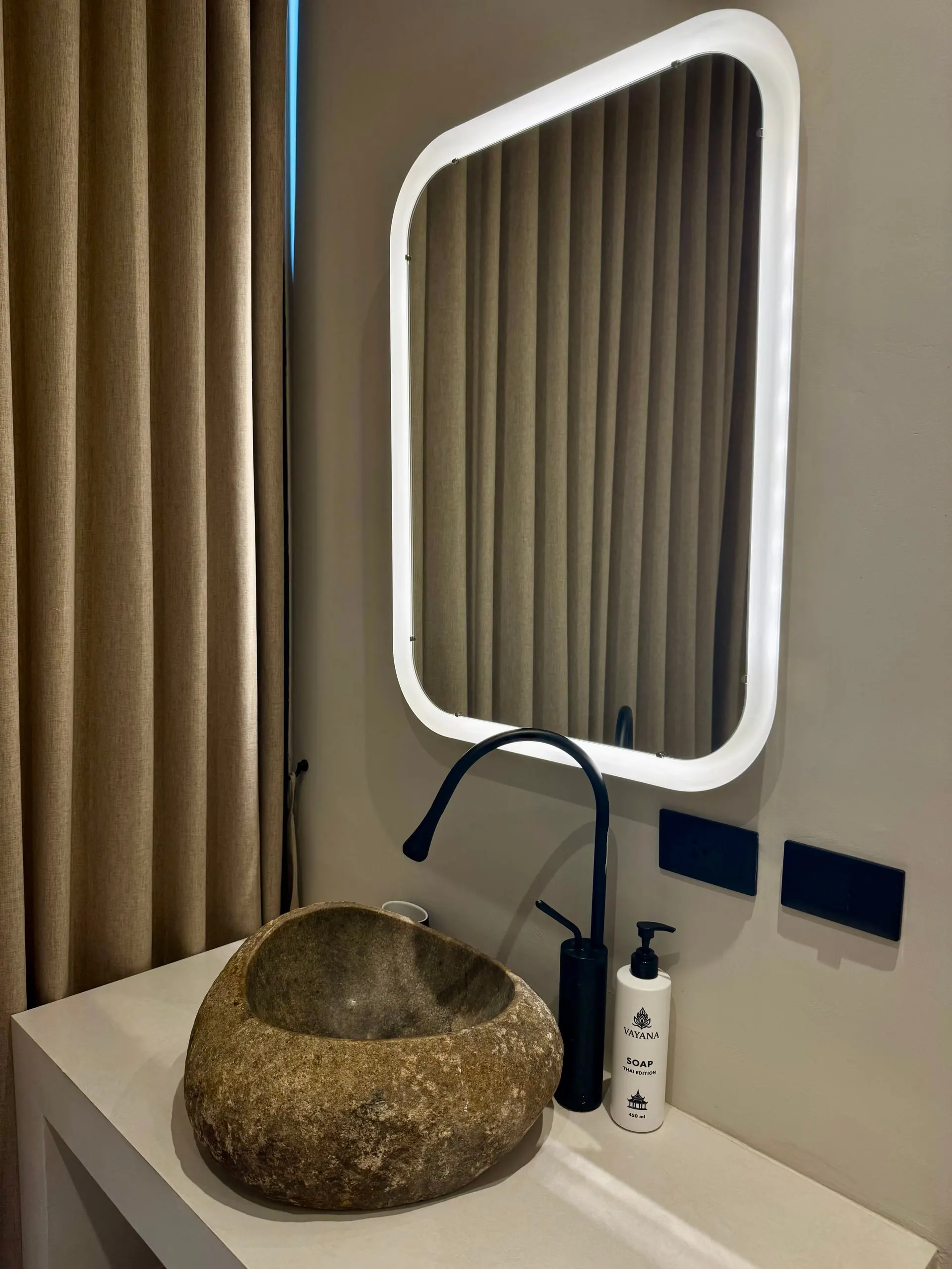 Villa I — bathroom two, natural stone basin beneath a backlit mirror